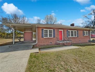 Charming brick home featuring a bright red front door and convenient covered parking area at 6120 E Fayetteville Dr, Riverdale, GA 30296