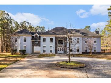 Stately home featuring a circular driveway, a three-car garage, and an elegant stone-accented facade at 9610 Cedar Grove Rd, Fairburn, GA 30213