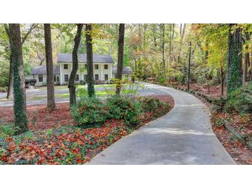 Beautiful two-story home with a winding driveway and a lush, wooded landscape at 7185 Peachtree Dunwoody Rd, Atlanta, GA 30328