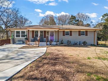 Charming single-story home featuring a well-manicured front yard, welcoming porch, and newly paved driveway at 4493 Old Hiram Lithia Spgs Rd, Powder Springs, GA 30127