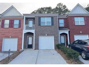 Three-unit brick facade townhomes feature individual garages and symmetrical window and door placement at 1530 Viero Dr, Lawrenceville, GA 30044