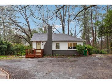 Charming home featuring a brick chimney, quaint porch, and light-colored exterior, nestled in a wooded lot at 1849 S Columbia Place, Decatur, GA 30032