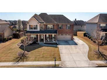 Beautiful two-story brick home featuring a well-maintained lawn, covered front porch, and attached two-car garage at 2401 Day Break Way, Dacula, GA 30019