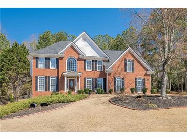 Charming two-story red brick home with black shutters and a well-manicured lawn and landscaped front yard at 4780 Woodruff Trce, Cumming, GA 30028