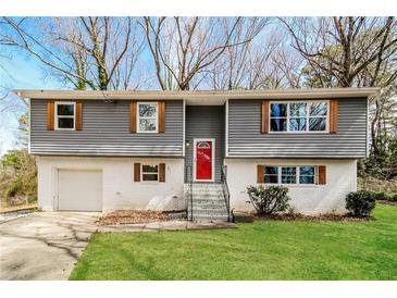 Charming split-level home with a red front door, wood accents, and fresh landscaping at 2330 Lago Dr, Jonesboro, GA 30236