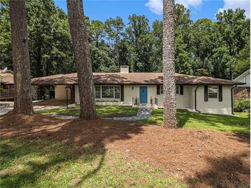 Charming single-story home with a well-maintained lawn, stone walkway, and a bright blue front door at 546 Milligan Dr, Stone Mountain, GA 30083