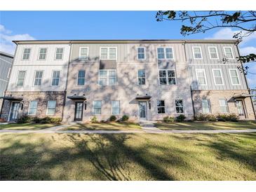 Modern townhome featuring a brick facade, gray siding, multiple windows, and a well-manicured lawn at 139 Jameson E Dr, Acworth, GA 30102
