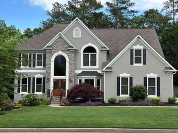 Charming two-story home with stone accents, lush lawn, and mature trees at 11935 Lexington Woods Dr, Alpharetta, GA 30005