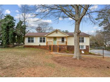 Inviting split-level home with a brick facade, cozy front porch, and beautiful mature trees at 2441 Hidden Hills Dr, Marietta, GA 30066