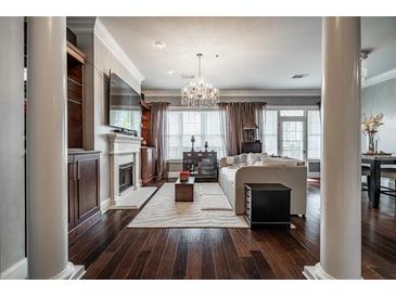 Bright living room featuring a fireplace, beautiful hardwood floors, large windows, and elegant lighting at 3280 Stillhouse Se Ln # 101, Atlanta, GA 30339