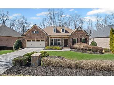 Charming brick home with a well-manicured lawn, complemented by a two-car garage and mature trees at 4930 Cecilia Sq, Cumming, GA 30040