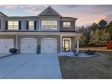 Charming townhome features a brick facade, attached garages, and a well-manicured lawn at dusk at 7207 Brigidoon Rose, Douglasville, GA 30134