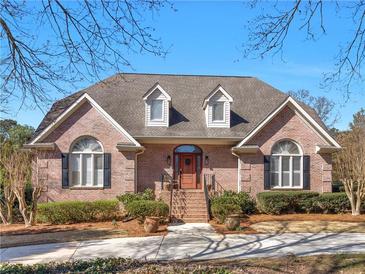 Charming brick home featuring an arched entryway, manicured landscaping, and symmetrical dormer windows at 8531 N Shore Dr, Jonesboro, GA 30236