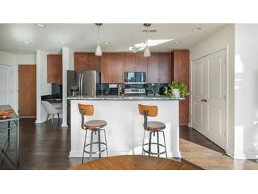Modern kitchen featuring stainless steel appliances, dark wood cabinets, and a breakfast bar with seating at 860 Peachtree St # 1418, Atlanta, GA 30308