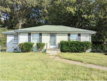 Ranch-style home with white brick exterior and a green roof, and overgrown lawn at 2022 Cook Rd, Decatur, GA 30032