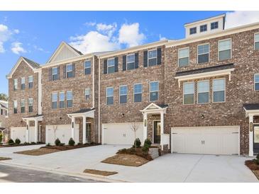 Charming brick townhomes feature attached garages, covered entries, and manicured landscaping under a bright blue sky at 3192 Eastham Run Dr, Dacula, GA 30019