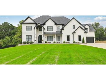 Stunning white two-story home with a manicured lawn, black trim, and a dark grey roof on a sunny day at 3735 Hamilton Mill Rd, Buford, GA 30519