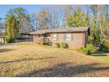 Charming brick home featuring a well-maintained lawn and covered front porch entry at 928 Magna Carta Nw Dr, Atlanta, GA 30318