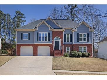 Charming two-story home featuring a brick facade, light blue siding, manicured lawn and attached two-car garage at 1772 Ascot Nw Run, Acworth, GA 30102