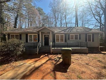 Charming one-story home with light green exterior, black shutters and front porch with black railing at 80 Harlan Sw Rd, Atlanta, GA 30311