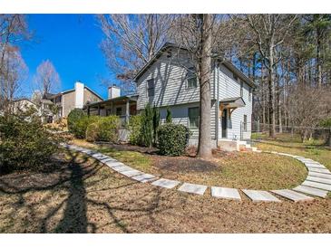 Charming home with a landscaped yard, stone walkway, and mature trees on a sunny day at 700 Hill Meadow Dr, Dacula, GA 30019