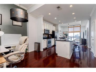 Bright, open-concept living space with hardwood floors, stainless steel appliances, and a breakfast bar at 3040 Peachtree Nw Rd # 1509, Atlanta, GA 30305