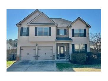 Charming two-story home featuring a two-car garage, well-maintained lawn, and inviting front entrance at 611 Winners Cir, Locust Grove, GA 30248