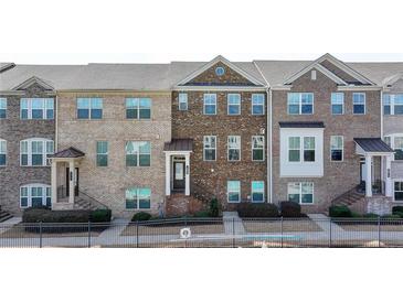 Attractive multi-story brick townhomes with manicured landscaping, and wrought iron railing at 656 Sunset Park Dr, Suwanee, GA 30024