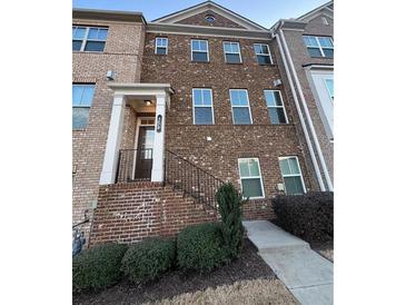 Beautiful brick townhome featuring a covered entryway and manicured landscaping at 656 Sunset Park Dr, Suwanee, GA 30024