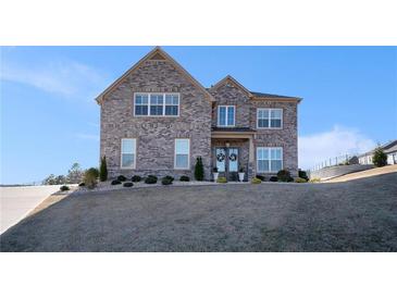 Two-story brick home featuring a well-manicured front lawn and charming architectural details at 1604 Falcon Ct, Locust Grove, GA 30248