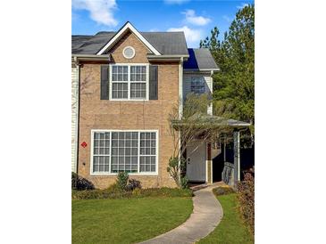 Charming multi-story townhome showcasing a well-manicured front lawn, brick facade, and welcoming front entrance at 217 Odyssey Turn Nw, Conyers, GA 30012