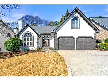 Charming traditional home featuring a 2-car garage, a manicured lawn, and a classic white stucco facade with black trim at 1230 Newbridge Ne Trce, Brookhaven, GA 30319