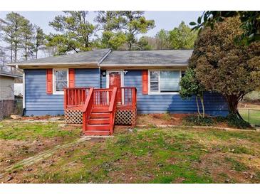 Charming blue house with a red front porch and shutters, nestled among trees with a well maintained lawn at 32 Hillcrest Se Dr, Austell, GA 30168