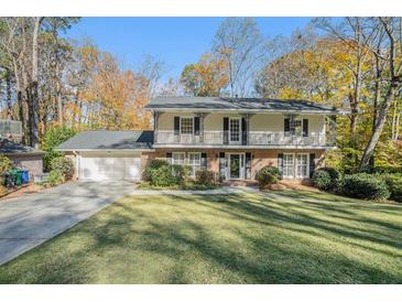 Charming two-story home with a manicured front lawn and classic architectural details in a lush, wooded setting at 1883 Acuba Ln, Atlanta, GA 30345