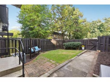 Serene fenced backyard featuring a swing, lush greenery, and a brick pathway at 290 Lakemoore Ne Dr # C, Atlanta, GA 30342