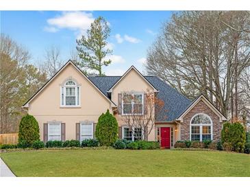 Charming two-story home with manicured lawn, a red door, and a mix of stone and siding accents at 4910 Hunters Oaks Ln, Alpharetta, GA 30009