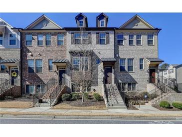 Charming townhome featuring a brick facade, landscaped front yard, and inviting entrance steps at 4498 Dunblane Ave, Sugar Hill, GA 30518