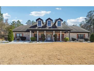 Charming brick home featuring dormer windows, a pillared porch, and manicured landscaping at 1369 Sierra Ridge Pl, Loganville, GA 30052