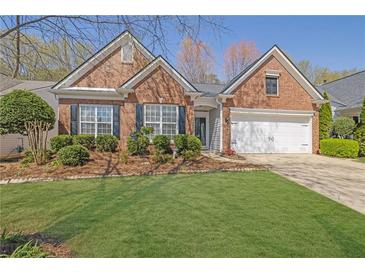 Charming brick home with a well-manicured lawn, beautiful landscaping, and an attached two-car garage at 6560 Waveland Dr, Cumming, GA 30040