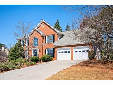 Charming two-story red brick home featuring a two-car garage and well-manicured landscaping at 1439 Evers Pl, Lawrenceville, GA 30043