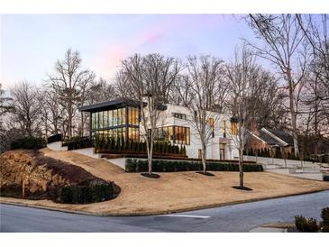 Stunning modern home featuring clean lines, a full-glass facade, and meticulously manicured landscaping on a multi-tiered lot at 14 Lake Forrest Ln, Atlanta, GA 30342