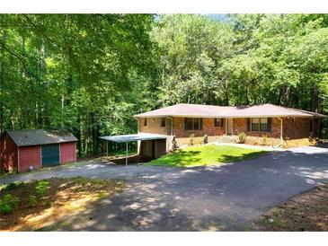 Ranch-style home features a brick exterior, carport and shed, nestled on a wooded lot at 6464 Westerly Way, Douglasville, GA 30135