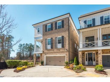 Charming brick home featuring an attached garage, a quaint balcony, and black shutters against a clear blue sky at 385 Rowes Cir, Alpharetta, GA 30009