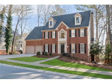 Two-story brick home featuring a manicured lawn, dormer windows, and attached two car garage at 1040 Longwood Dr, Woodstock, GA 30189