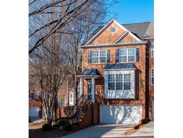Charming brick townhome featuring a front-facing garage, black shutters, and inviting front entrance at 401 Iona Abbey Se Ct # 6, Smyrna, GA 30082