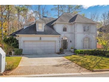 Elegant two-story home featuring a brick driveway, lush lawn, arched windows, and a two-car garage at 1139 Tennyson Ne Pl, Brookhaven, GA 30319