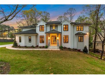 Beautiful two-story home featuring a painted brick facade, black trim, and lush green lawn at twilight at 3968 Ashford Dunwoody, Brookhaven, GA 30319