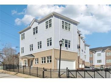 Beautiful three-story home featuring light blue siding, white trim, and a brick base with an attached garage at 2000 Ocean Nw Dr, Atlanta, GA 30318