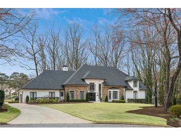 Elegant stone and white home with a well-manicured lawn and circular driveway, offering curb appeal at 1460 Lakemist Ct, Roswell, GA 30075