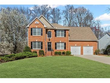 Charming two-story red brick home featuring a manicured lawn, black shutters and a two car garage at 1760 Clayton Cir, Cumming, GA 30040